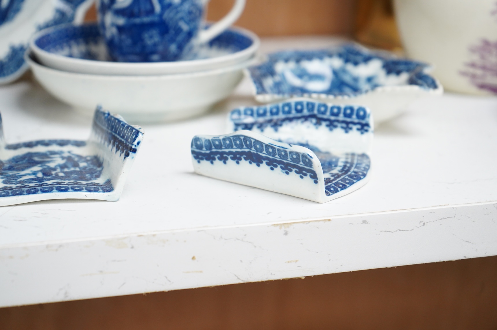 A group of 18th century Worcester or Caughley blue and white ‘Fisherman and Cormorant’ pattern wares; two asparagus dishes, three leaf pickle dishes, a cup and two saucers and a large dish- 18cm diameter (9).